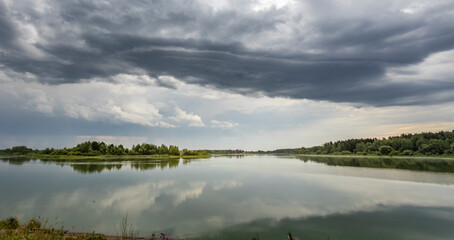 A cloudy sky over a lake with trees in the background
