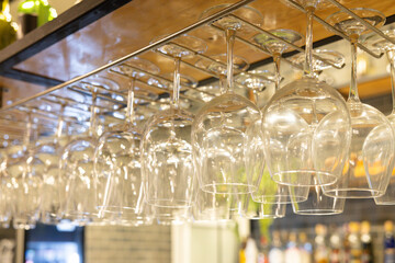 A row of wine glasses are hanging from a rack
