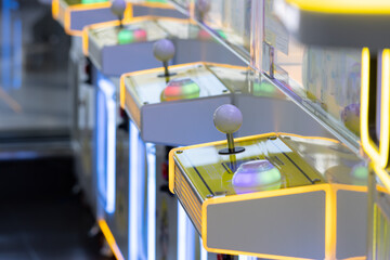 A row of arcade games with neon lights and buttons