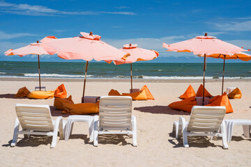 Cafe sunbed chairs and orange beanbag seats on Cha Am beach