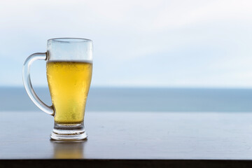 Craft beer in grass on wooden table with horizon sea, Hua Hin