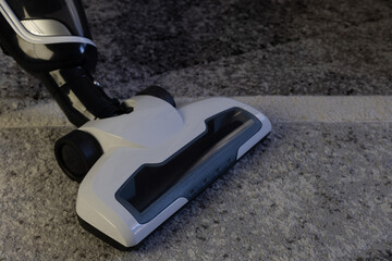 Fototapeta premium A small portable vacuum cleaner standing on the carpet in the living room, cleaning the apartment before Christmas