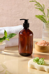 An amber pump bottle without label placed in center with many stocks of spa theme decorated around. Close up front angle shot, mock up for advertising