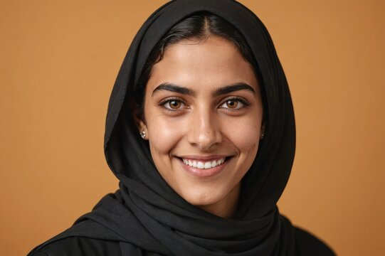 Full framed very close face portrait of a smiling young arabic non binary with amber eyes looking at the camera, studio shot,amber background.