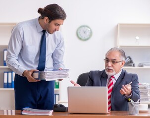 Old boss and young male employee in the office