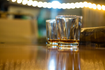 Vodka in shot glasses on the table with a bokeh background.