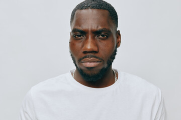 Portrait of a confident man with a serious expression, wearing a simple white t shirt, standing against a light gray background The subject exudes strength and determination, offering a powerful vis