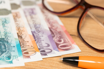 British pounds money on the desk next to womens glasses and pen, concept, payment of bills, installments and loans, rising costs of household budget in the UK