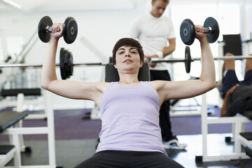 Woman, dumbbells and exercise in portrait on bench for training, wellness or muscle development at gym. Person, weightlifting and workout for bodybuilding, fitness or power with strong arms in Greece