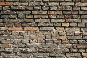 Aged brick wall of an old tenement house. Cracked and chipped surface with grunge texture. Historic...