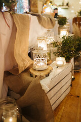 Boho wedding decoration. Rustic decorations of wedding venue. Romantic atmosphere. Wooden box and white candles. Vintage style interior. Wedding party in a barn.