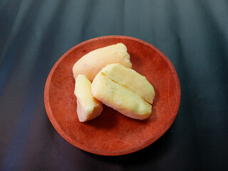tape or traditional Indonesian food made from fermented cassava served on a wooden plate on a black background. Tape or tapai or peuyeum. cassava tape