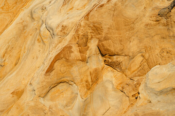 Natural texture background of sandstone rocks with lines, curves, prints in the As Amoeiras and Formosa beach cliffs in Santa Cruz, Portugal.