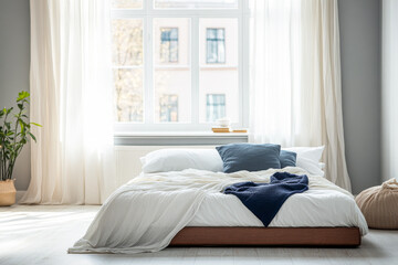 Cozy bedroom with natural light and minimalist decor featuring a soft bed with cushions in a tranquil setting during daylight hours
