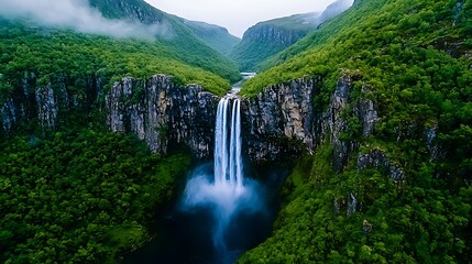 Obraz premium A majestic waterfall tumbles through lush green mountains, nature�s power in full display.