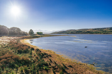 The powerful rays from the Sun cast a warming light over an idyllic landscape in the banks of the River Ebro reservoir in Cantabria, Spain