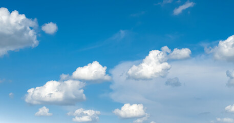 the sky is clear blue with fluffy white clouds, the sky is very bright, and the sun shines.
