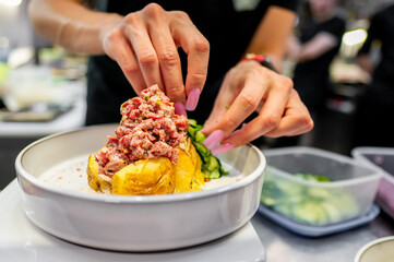 A close-up of hands preparing a dish with minced meat and vegetables, showcasing fresh ingredients and culinary skill. Ideal for culinary blogs, recipe websites, or cooking magazines.
