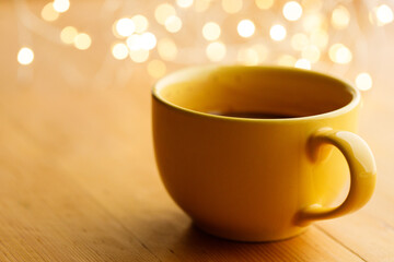 Cup of delicious hot chocolate under with light bokeh on wooden table background. Selective focus.
