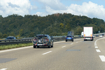 Bicycles fixed to cars move along the motorway.