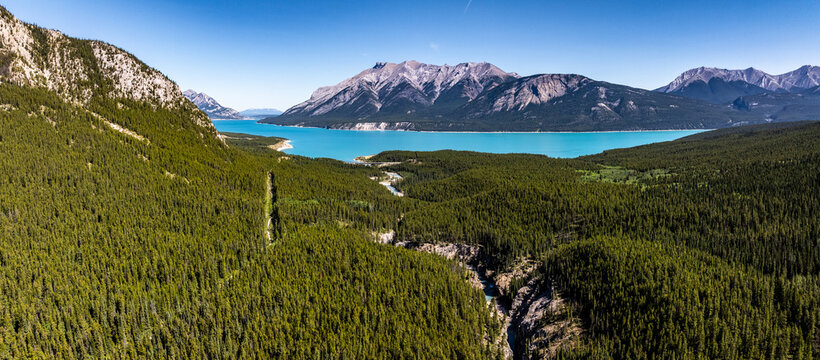 Canadian aerial landscape view along river course of Cline river with deep gorge and river mouth into North Saskatchewan River as well Abraham Lake and Rocky Mountains in background