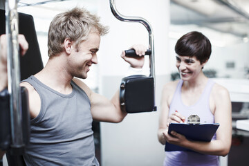 Personal trainer, clipboard and people with workout in gym for training equipment, coaching or notes. Man, fitness and woman with checklist in session for exercise, help or tracking progress on paper