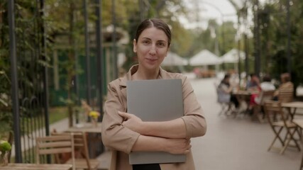 Brunette Businesswoman Holding Laptop, Preparing for Remote Work on Terrace