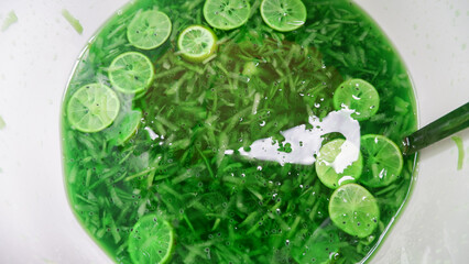 Green ice cold drink mixed with cucumber slices and orange pieces. refreshing drink