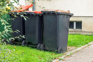 Outdoor trash bins, green grass, asphalt path, residential area, waste management concept