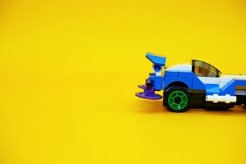 blue racing car assembled from plastic blocks. toy car isolated on yellow background
