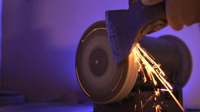 close up of sharpening an axe on a machine with a grinding stone. Sparks