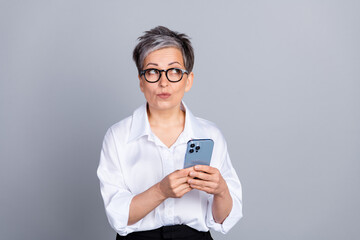 Photo portrait of attractive pensioner woman look wondered empty space device dressed stylish...