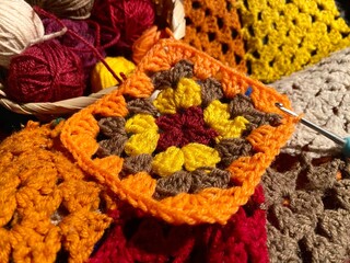 Crochet granny square, clews and hook on crochet blanket background photo 