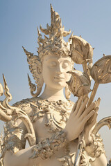 A statue of a mythological creature, guardian, angel, spirit, phaya naga, dragon holding flowers at the White Temple, Wat Rong Khun, Chiang Rai, Thailand