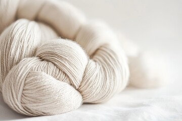 A soft beige yarn lies gracefully on a light background, highlighting its delicate texture, perfect for crafting and knitting projects