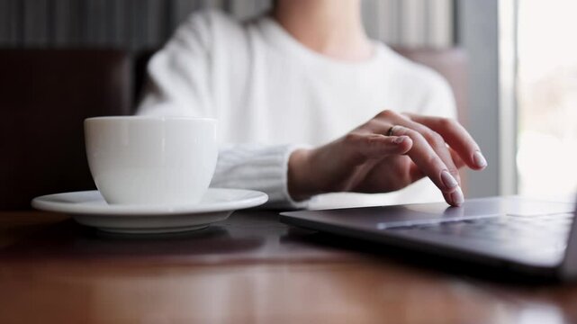 Close-up of hands of unrecognizable businesswoman typing on laptop keyboard while working online. The concept of remote work online, freelancing and successful business.