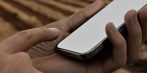 Caucasian White male using smartphone with a blank white screen. Field, agriculture, farming apps mockup. Vertical phone orientation
