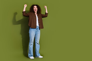 Full size photo of pretty young woman raise fists empty space isolated on khaki color background