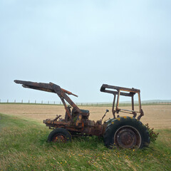 Old style farm tractor sitting on a green grass field. Isle of North Uist, Scotland