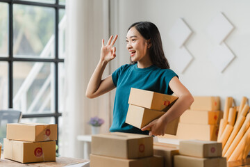 Successful Small Business Owner: A young woman entrepreneur, radiating positivity, holds up a stack...