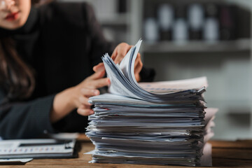 Overwhelmed by Paperwork: A businesswoman grapples with a mountain of paperwork, her face obscured...