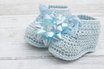 Blue baby booties with a bow on wood