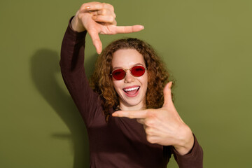 Photo of adorable lovely girl wear brown shirt showing arms photo gesture empty space isolated khaki color background