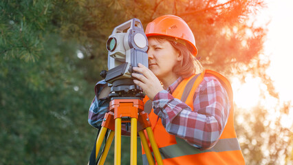 A female surveyor engineer with a total station. The geodetic instrument stands next to the geodesy...
