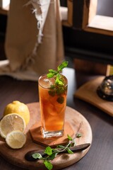 cup of tea, This photo features a glass of cold beverage, possibly lemon iced tea, served in a tall glass with ice cubes and fresh mint leaves as garnish.