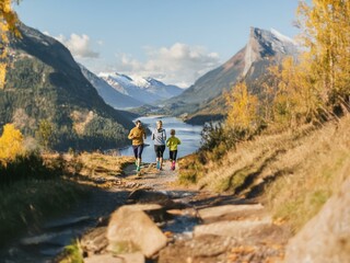 Fototapeta premium A family of four is running on a dirt path in the mountains. The path winds through a valley with a lake in the distance.