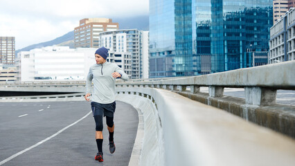 Fitness, running and man in city for exercise, training or cardio for healthy body. Sports, jog and runner on street outdoor for wellness, energy or workout to lose weight or race in winter on bridge