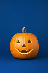 Obraz premium A Halloween pumpkin with a carved face on a blue background, a studio shot, minimalist design.