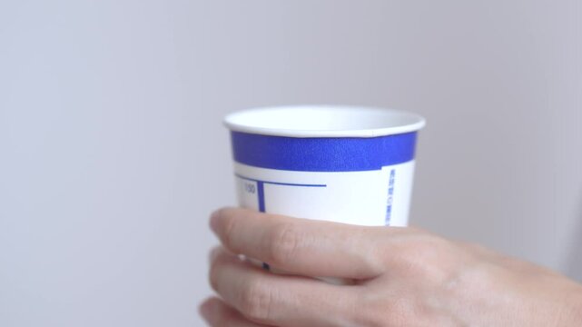 health check.  Person holding a urine test cup.  健康診断。検尿カップを持つ人