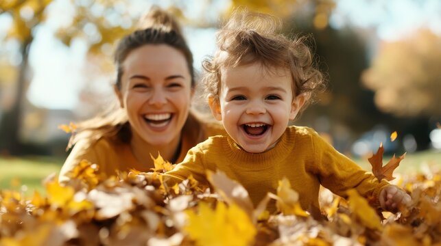 A toddler and mother share a playful and tender moment, enjoying the warmth of each other’s company under the golden hue of the fall leaves in a serene park.